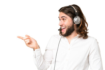 Telemarketer man working with a headset over isolated chroma key background pointing finger to the...