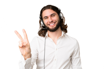 Telemarketer man working with a headset over isolated chroma key background smiling and showing victory sign