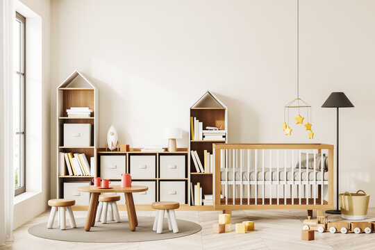 Beige baby room interior with crib, table and stool, shelf with decoration