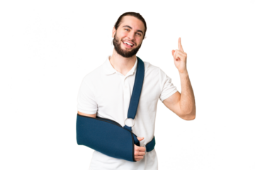Young handsome man with broken arm and wearing a sling over isolated chroma key background showing and lifting a finger in sign of the best
