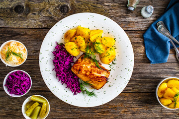 Fried pork loin with boiled potatoes and red cabbage on wooden table
