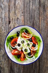 Fresh vegetable salad with feta cheese on wooden table
