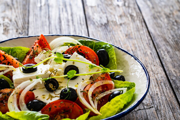 Fresh vegetable salad with feta cheese on wooden table
