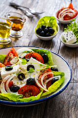 Fresh vegetable salad with feta cheese on wooden table
