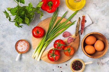 Prepared ingredients for cooking shakshuka, fried eggs with tomato stew on a gray concrete background. Hearty breakfast recipes.
