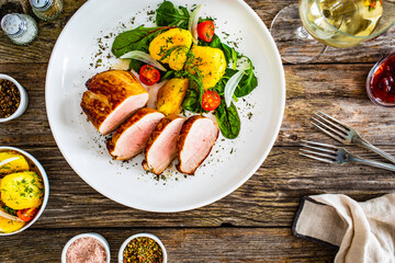 Fried pork loin with fried potatoes and vegetables on wooden table
