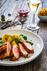 Fried pork loin with fried potatoes and vegetables on wooden table
