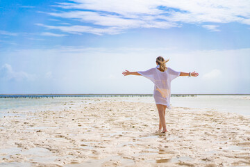 Beach holiday - woman walking on sunny, tropical beach during water outflow

