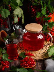 Red currant tea in a glass teapot on a dark background with berr