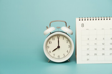 close up of calendar and alarm clock on the green table background, planning for business meeting or travel planning concept