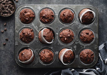 Overhead of tin of chocolate zucchini muffins on black background.