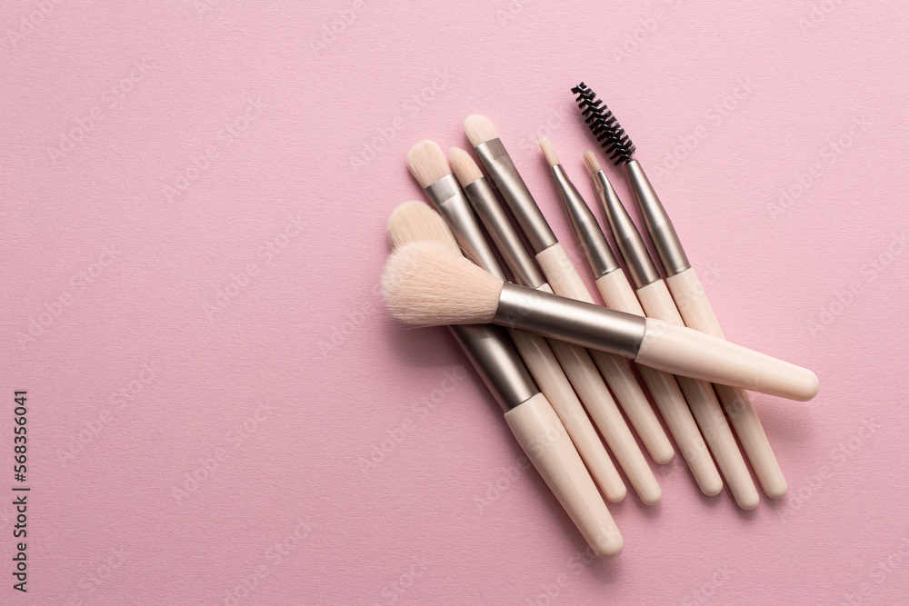 Wall mural set of makeup brushes on soft pink colored background. top view, flat lay.