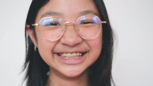 Asian girl wearing eyeglasses smiling brightly showing off her braces