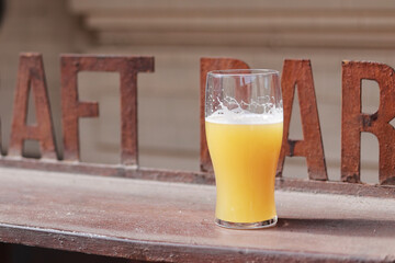A glass of started beer. A pint of unfiltered APA on the bar. - obrazy, fototapety, plakaty
