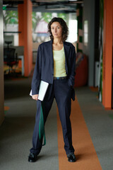 confident business woman standing and looking at the camera holding laptop, vertical photo . High quality photo