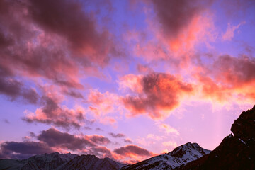 Bizarrely interesting sunset clouds over snow-capped mountain peaks