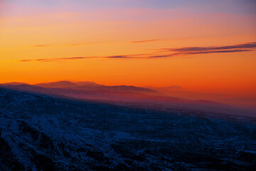 Magical atmosphere of a sunset in the highlands; sunset sky over snow-capped mountain ridges