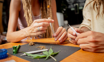 Hippie style couple making medical marijuana cigarettes