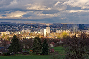 Fototapeta premium Scenic view over Glatt Valley with skyline of village of Wallisellen seen from City of Zürich district Schwamendingen on a cloudy winter evening. Photo taken February 4th, 2023, Zurich, Switzerland.