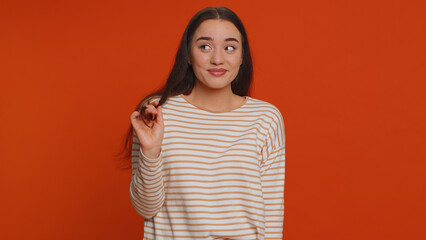 Smiling playful pretty young woman in pullover blinking eyes, looking at camera with toothy smile,...