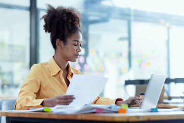 Young African American businesswoman working with pile of documents at office workplace, business finance and accounting concepts.