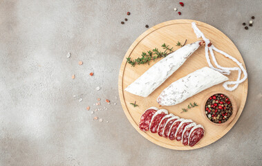 Fuet, traditional spanish dry cured sausage on a wooden board on a light background. banner, menu,...