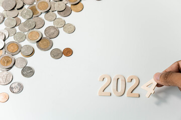 Hand putting wooden text of 2024 with coins, money saving concept, financial, white background