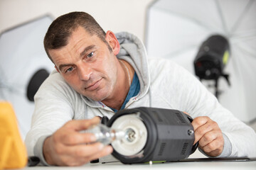 male photographer preparing lighting equipment in studio