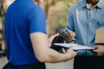 Male appending signature sign on paper for sending boxes with delivery man, Asian man signed with an paper signature on the box, Concept of parcel delivery.