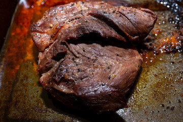 Well cooked medium rare pork stake on greasy cooking pot close up shot.