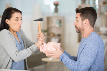 couple poised to smash piggybank with a hammer