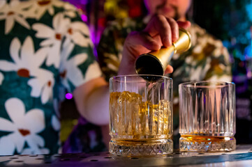 Fototapeta premium Bartender hand pouring whiskey on glass in bar