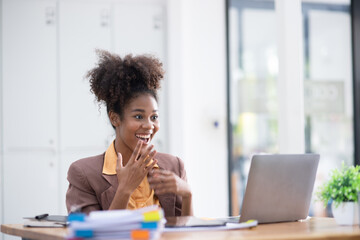 Young African American woman very happy and excited doing winner gesture with arms raised at table office, Business success and celebration concept.