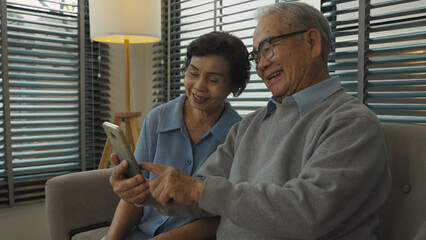 Happy Retired couple family spouses having fun use smartphone at home