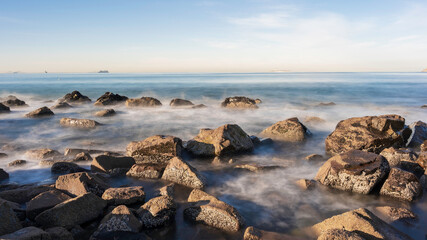 Fototapeta na wymiar Rocks on the shoreline of a California Beach. Long Exposure so the sea is smooth. Room for Copy.