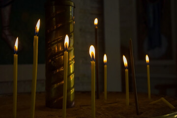Burning candles in church. Burning candles shining in dark background. Copy space. Close-up. Shallow depth of field.
