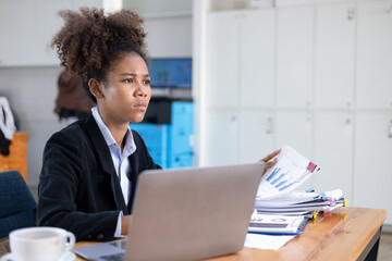 Young African American businesswoman working on laptop with documents and stressed over worked from work in the office, Overworked woman concept.