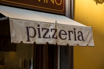 Foto auf Glas A Pizzeria Awning with the word pizzeria on a facade of a restaurantin Italy. © Krasi Kanchev