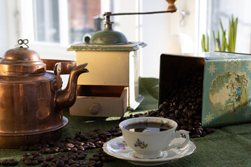 Coffee grinder and a coffee pot with some coffee beans and a coffee cup