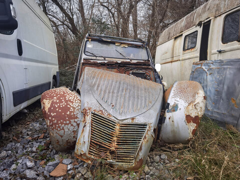Carro cl&aacute;ssico abandonado e enferrujado a meio de outros carros na mesma situa&ccedil;&atilde;o, para pe&ccedil;as ou abate
