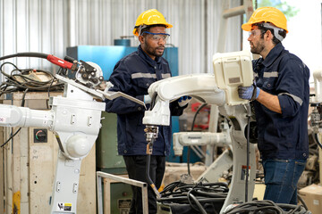 Industrial engineer using remote control board to check robotic welder operation in modern...