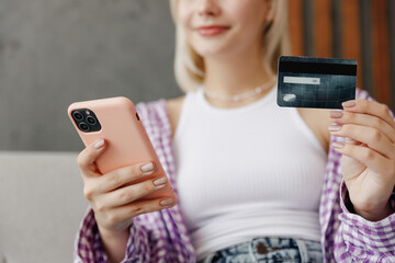Cropped young woman in casual clothes hold mobile cell phone credit bank card shopping online book...
