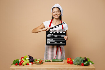 Young fun housewife housekeeper chef latin woman wear apron toque chefs hat work at table...