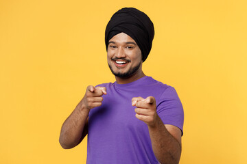Smiling happy devotee Sikh Indian man ties his traditional turban dastar wear purple t-shirt point...