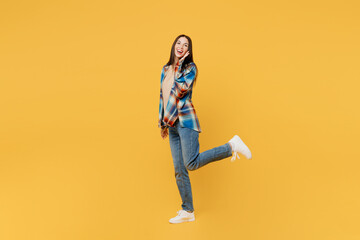 Fototapeta na wymiar Full body side view cheerful happy young smiling woman wears blue shirt beige t-shirt look camera hold face look camera isolated on plain yellow background studio portrait. People lifestyle concept.