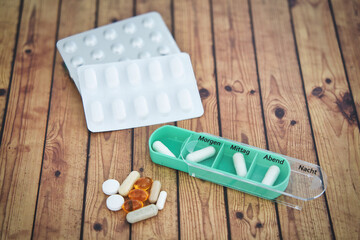Daily green drug dose - pills organized in a pill box, german letters means monday - sunday,...
