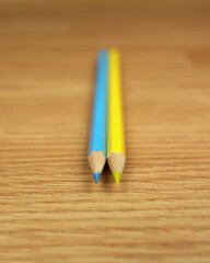 Obraz premium Two blue-yellow pencils on a wooden background, like the flag of Ukraine. Preparation for study