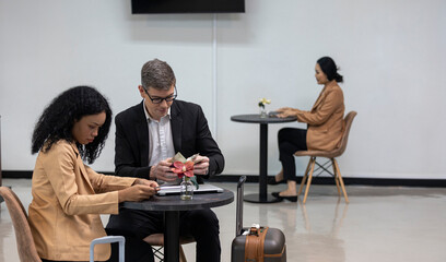 Two business workers are waiting and taking facility service at an exclusive airline lounge. Travelers get refreshment at a private lobby to be ready for their trip.