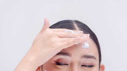 Woman wipes the facial wash foam off her forehead. Young lady lathering the whitening soap on her...