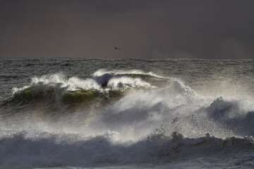 Breaking wave against rainy sky